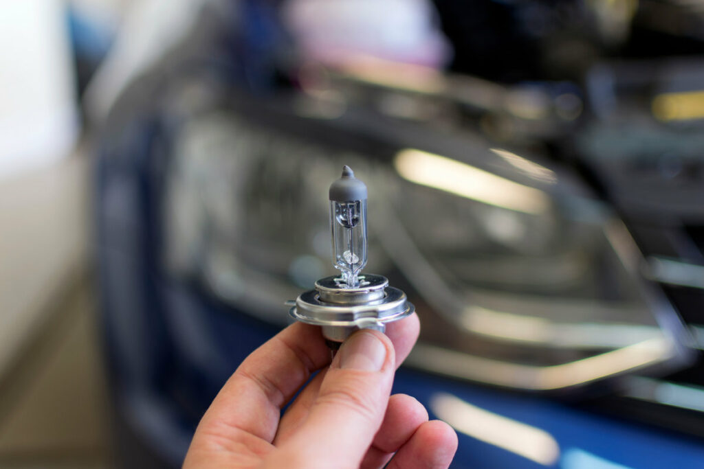 mano che tiene una lampadina di un faro auto