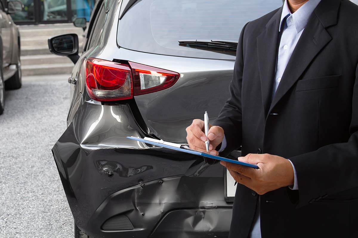 Perito assicurazione che controlla di danni all'auto dopo un incidente