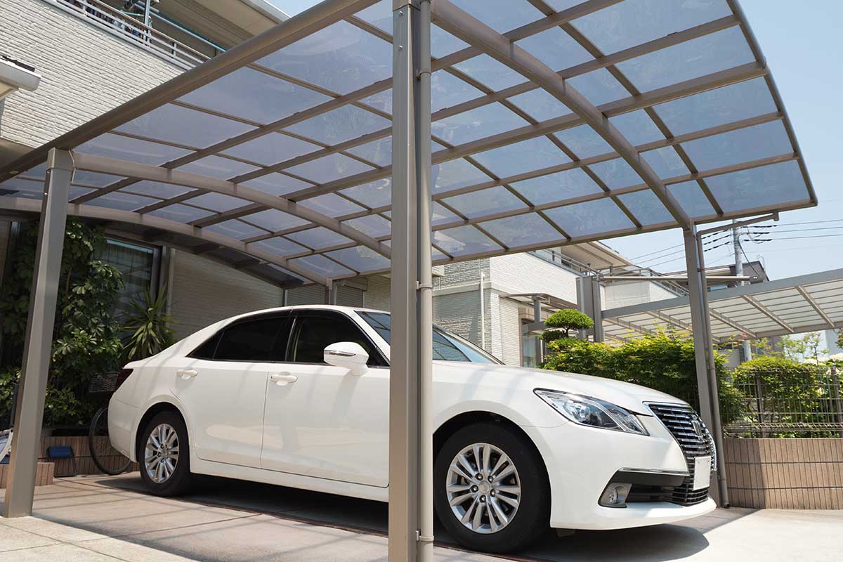 Auto bianca parcheggiata al ripato sotto una tettoia di metallo e plexiglass