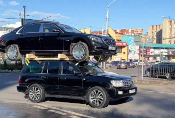 Auto ne trasporta un'altra sopra al tettuccio