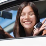 ragazza sorridente con le chiavi dell'auto nuova in mano