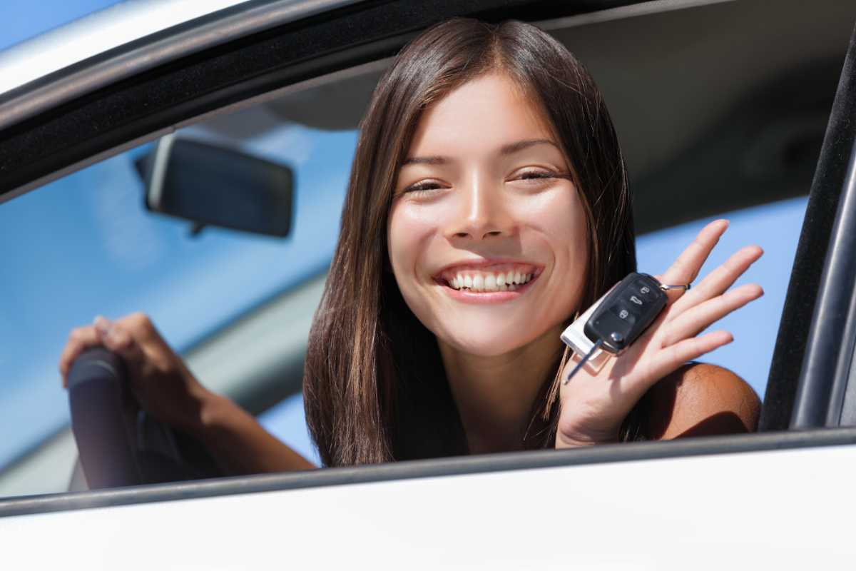 ragazza sorridente con le chiavi dell'auto nuova in mano